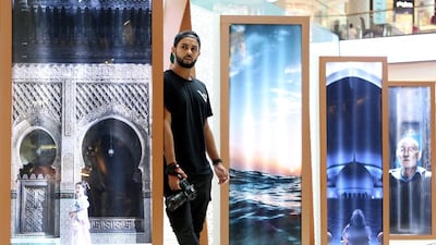 Aqib Anwar poses for a photograph in front of his art on display at the Dubai Mall. Satish Kumar / The National