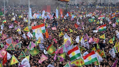 Smoke rises from a fire burning as people wave Kurdish flags and pictures of jailed Kurdish rebel leader Abdullah Ocalan as they gather to celebrate Newroz, the Kurdish New Year, in the southeastern Turkish city of Diyarbakir on March 21, 2015. Ilyas Akengin/AFP Photo