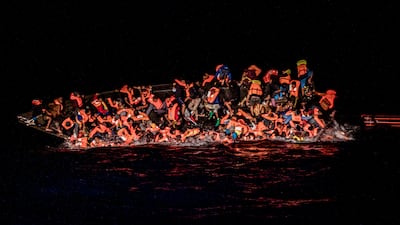 Dozens of migrants cling to the side of a sinking boat in the waters off Tunisia on Wednesday. AP