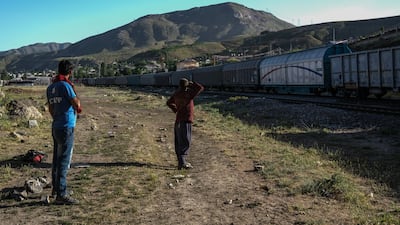 Afghans wait for the freight train to slow down under a bridge near the railway in Van city after crossing the Iran-Turkey border near Tatvan district in Bitlis city, eastern province of Turkey.