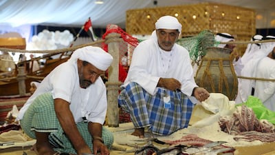 Mohammed Suliman Abdullah Al Dhuhoori, left, cuts up fish.