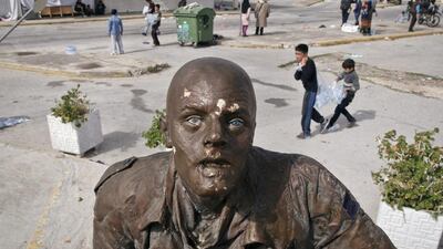 Refugee children carry bottles of water passing behind a statue depicting an air traveller at the old airport in Athens. Vadim Ghirda / AP Photo