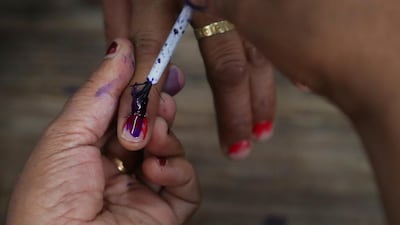 A polling officer puts an indelible ink mark on the finger of a voter before she casts her vote in New Delhi, India, on Sunday, May 12, 2019. AP Photo