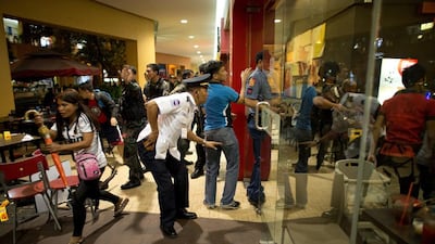 Diners rush from a restaurant as an officer from the Philippines police moves towards the scene of an attempted robbery on a jewellery store inside SM Mall of Asia in Manila on March 30, 2014. Noel Celis / AFP