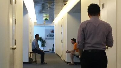 Investors and staff sit outside the closed office of Exential at Arenco Tower in Dubai Media City in Dubai, in January 2016. Pawan Singh / The National