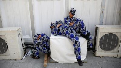 Security personnel take a nap behind one of the halls of Auto China 2016 auto show in Beijing. Damir Sagolj / Reuters