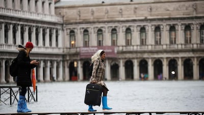 People use trestle bridges to walk in a flooded St. Mark's Square at Venice, Italy. AP Photo