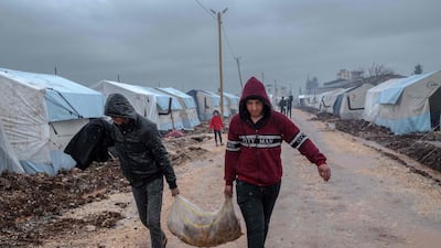 Men carry a sack of potatoes at a camp for people displaced by the February 6 earthquake, in Turkey's Adiyaman province. AFP