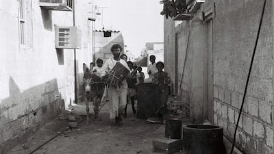 Drummer Khamees, an Abu Tabla, walks the alleyways of Abu Dhabi with his entourage to wake people for the day’s fasting in the 1970s. Photo: Al Itihad