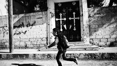 A young boy runs outside an abandoned Syrian Orthodox church in Ras Al Ain. Most of the Christians who used to live there left when the Islamists took control. When the Kurdish YPG - People's Protection Units retook control of the town some of Christian families returned.