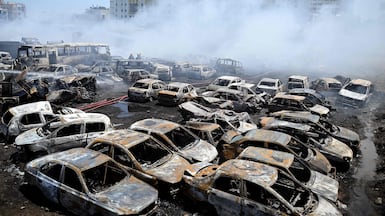 Firefighters douse burnt-out cars after a fire at a dumpyard in Chennai, eastern India. AFP