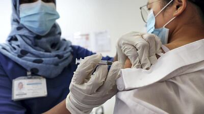 A nurse gives a patient a vaccine shot in Dubai. The UAE had administered 51.11 vaccine doses for every 100 people as of Sunday, second only to Israel Pawan Singh / The National