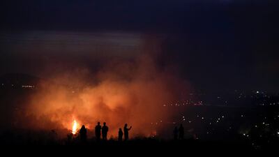 People watch as a wildfire burns along a hillside in Southern California. Jae C Hong / AP Photo