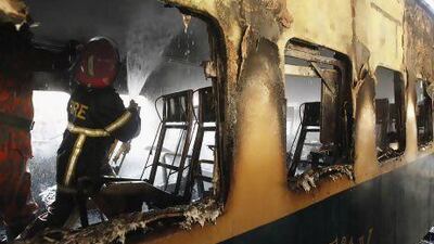 A fire fighter sprays water inside the burnt compartment of a train at Kamlapur Railway Station in Dhaka on Monday. Andrew Biraj / Reuters