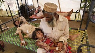 A Pakistani man holds his granddaughter, who is suffering from dehydration and a fever, in the Chota Lahore relief camp in Swabi.