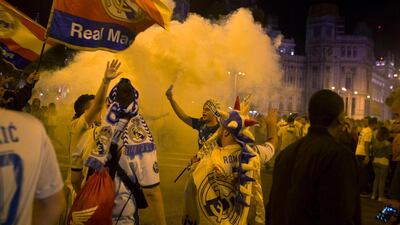 Real Madrid fans celebrate after lighting a flare in downtown Madrid, Spain. Paul White / AP Photo