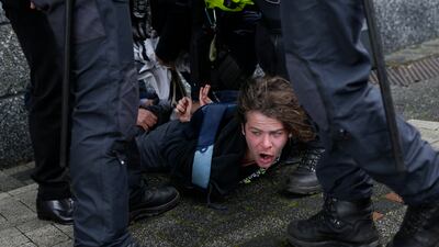 A protester is pinned to the ground by guards after he ran towards French President Emmanuel Macron outside the University of Amsterdam in the Netherlands on Wednesday. AP