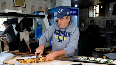 Abu Shadi cuts a freshly baked garnished flatbread before serving it to a customer. AFP
