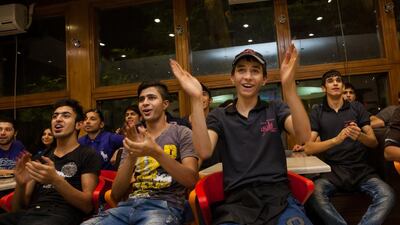 Some of the young workers at the restaurant watching the game at the restaurant that they work in.