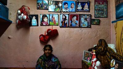 Patient Draupadi, 47, also cured of leprosy poses with pictures of her family.