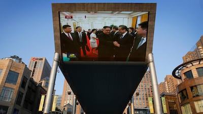 People cycle past a giant TV screen in Beijing broadcasting the meeting. Andy Wong / AP Phoyo