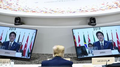 Mr Trump sits before screens showing Mr Abe during a meeting. AFP