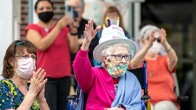 Carol Reihart, a certified nursing assistant at Little Sisters of the Poor, and resident Kay Canyock wave to cars filled with family, friends, and volunteers during a parade to celebrate Canyock's 100th birthday and the birthday of fellow resident Mary Sahayda, who turned 103 on the same day, at Little Sisters of the Poor home for the elderly in Pittsburgh, Pennsylvania, USA. Pittsburgh Post-Gazette via AP