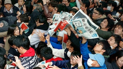 People reach out for copies of newspaper reporting the name of new era "Reiwa" in Osaka. AP