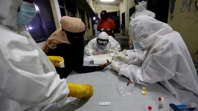 Healthcare workers in hazmat suits collect samples from a Rohingya refugee for a Covid-19 coronavirus rapid test after the refugees disembarked from a boat upon arrival at Lancok beach, North Aceh, Indonesia EPA