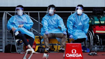 Medical officers wearing protective suits are seen at the morning session of the athletics test event. Reuters