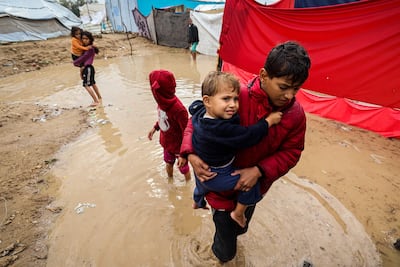 Palestinian children wade though flood water in Gaza. AFP