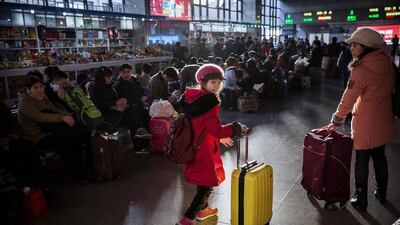 A young Chinese traveller wheels her bag as others wait in the departure area for a train at a local railway station on February 16, 2015 in Beijing, China. Millions of Chinese will travel home to visit families in mass during the Spring Festival holiday period that begins with the Lunar New Year on February 19. Kevin Frayer / Getty Images