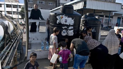 Palestinians, displaced by violence and living at a UN school in Gaza City, fill up their plastic jugs as a water supply truck makes its daily delivery (AFP PHOTO/ROBERTO SCHMIDT)