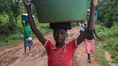 A young man poses for a portrait while carrying belongings in a tub on his head in Chipinge, Zimbabwe. Getty Images
