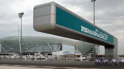 Riders pass under the giant Yas Marina Circuit sign during a training ride on the track.