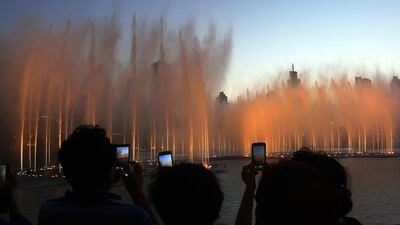 Tourists take photos of the fountain at the Burj Khalifa lake in Dubai . Satish Kumar / The National