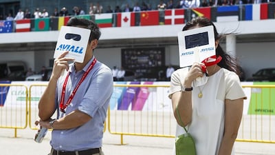 Spectators use handheld sunshades as they watch an aerial display during the Singapore Airshow. Wallace Woon / EPA