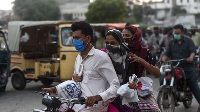 People riding a motorbike carry food packets distributed by a citizen at a roadside after the government eased the nationwide lockdown imposed as a preventive measure against coronavirus, in Karachi. AFP