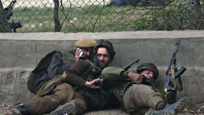 Indian policemen take cover during a gun and grenade battle in Srinagar which left five soldiers and two militants dead, and another 10 people wounded.