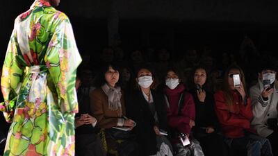 Guests wear protective masks as a model presents a creation by Dries Van Noten during the Women's Fall-Winter. AFP