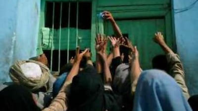 A crowd reaches for a piece of meat distributed from the door of a mosque in Kabul, Afghanistan.