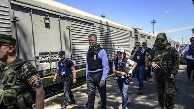 Monitors from the Organisation for Security and Cooperation in Europe (OSCE) and members of a forensic team inspect a refrigerator wagon containing the remains of victims from the downed Malaysia Airlines Flight MH17, at a railway station in the eastern Ukrainian town of Torez on July 21, 2014. Bulent Kilic/AFP Photo