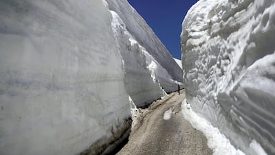 People take pictures on a road, surrounded by 10m walls of snow, on May 28, 2019, in the northern Lebanese village of Ainata al-Arz, 1620 m above sea level. AFP