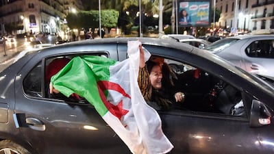 An Algerian holds a national flag while sitting out the window of a car during a demonstration in the centre of the capital Algiers on March 11, 2019, after President Abdelaziz Bouteflika announced his withdrawal from a bid to win another term in office and postponed an April 18 election, following weeks of protests against his candidacy. Bouteflika, in a message carried by national news agency APS, said the presidential poll would follow a national conference on political and constitutional reform to be drawn up by the end of 2019. / AFP / RYAD KRAMDI
