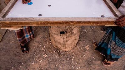 With few options for recreation, labourers spend the early evening playing games such as 'lamboard', while drinking cups of tea and smoking cigarettes.