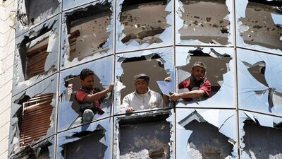 Workers clear broken glass from windows at a group of companies belonging to business tycoon Tawfeek Abdo Al Raheem, which was damaged by fighting between Shiite Houthi rebels and government forces in Sanaa on Sunday. Mohamed Al Sayaghi / Reuters