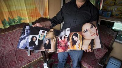 A wedding photographer proudly shows his bridal portraits at his photo studio.