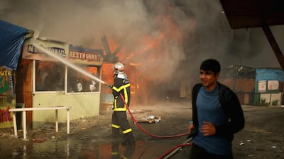 Migrants leave the Jungle camp as fires rage on October 26, 2016. Getty Images