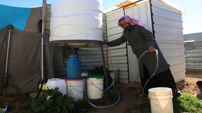 A Syrian man fills a bucket with water inside Zaatari, the largest camp for Syrian refugees in Mafraq, Jordan. Syrians benefit local economies, say the WFP. (AP)