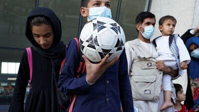 A boy holds a football as he and other Afghan refugees board a bus taking them to a processing centre upon arrival at Dulles International Airport on Friday. Reuters